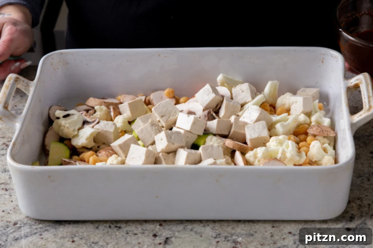 Adding cubed tofu to the bowl of chickpeas and vegetables.