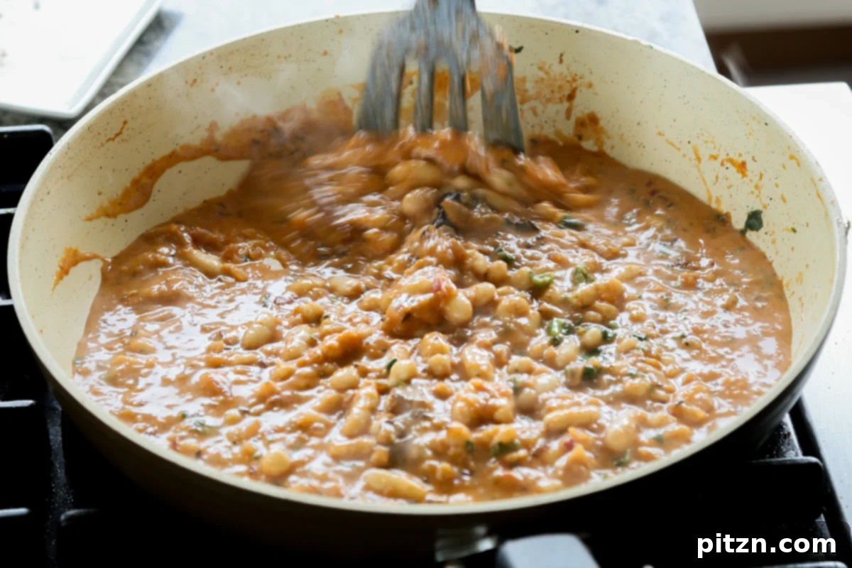 The white beans and spinach being gently mixed into the rich, creamy Dhaba curry sauce.