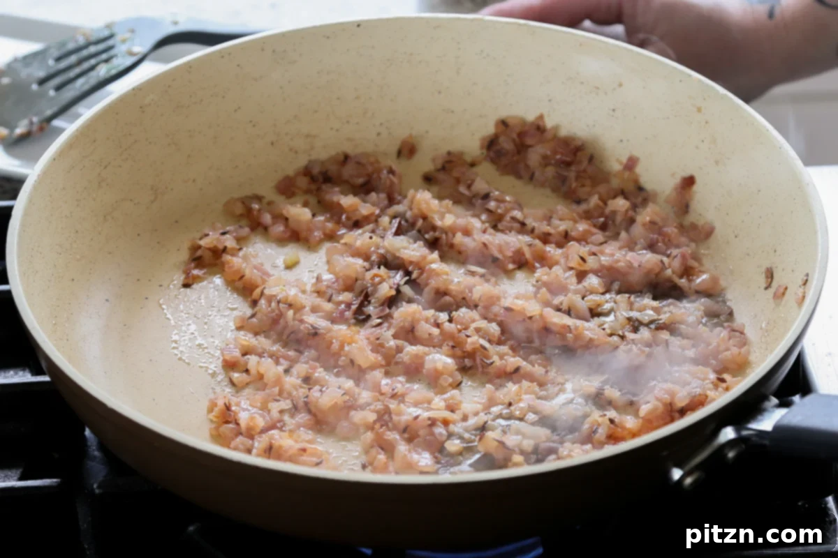 Cooked, golden-brown onions in the pan, forming a rich base for the curry.