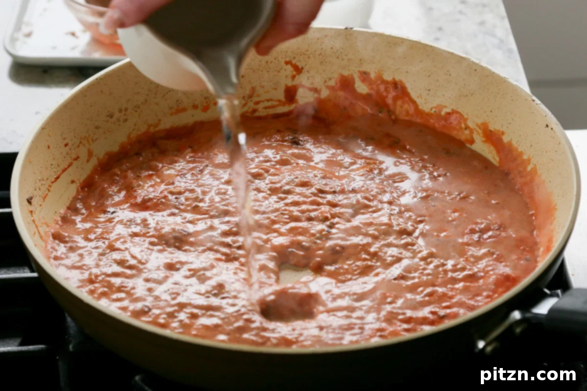 Effortless Rosé Beans for All 10 Pouring water into the simple rosé sauce mixture in the pan.