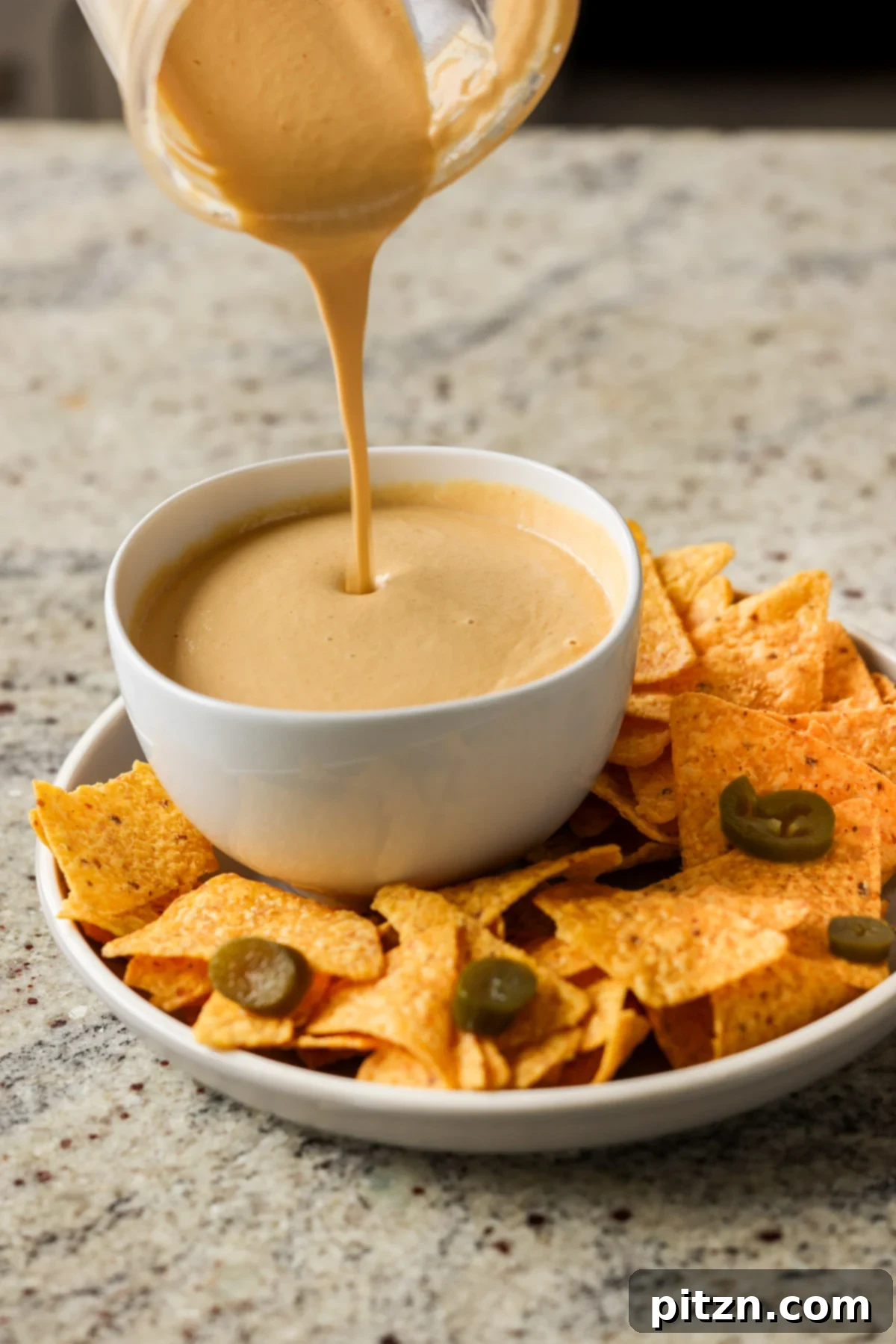 Amazing Cashew Nacho Cheese Gluten Free Oil Free Soy Free Choice 3 Pouring a thick, golden stream of creamy cashew nacho cheese into a pristine white serving bowl