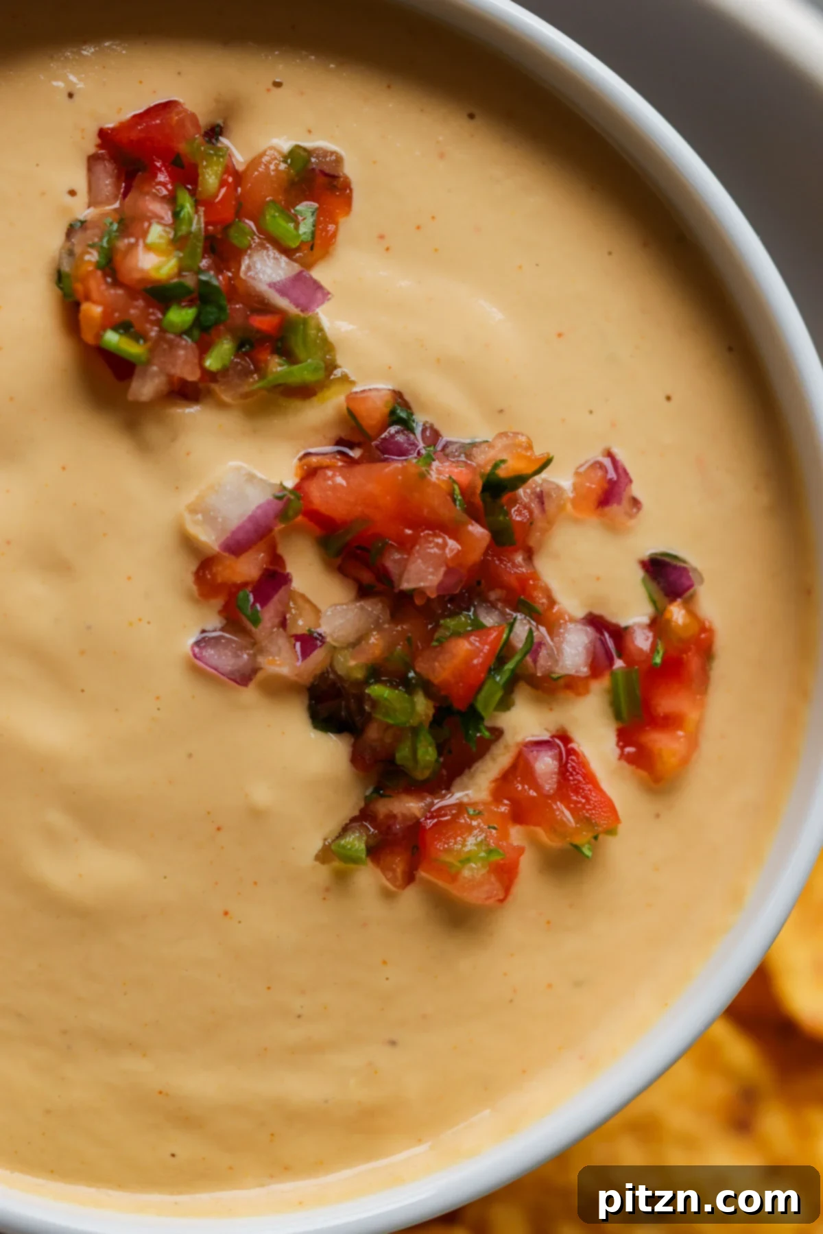 Amazing Cashew Nacho Cheese Gluten Free Oil Free Soy Free Choice 5 Close-up of a serving bowl filled with creamy cashew nacho cheese, beautifully garnished with vibrant red salsa on top