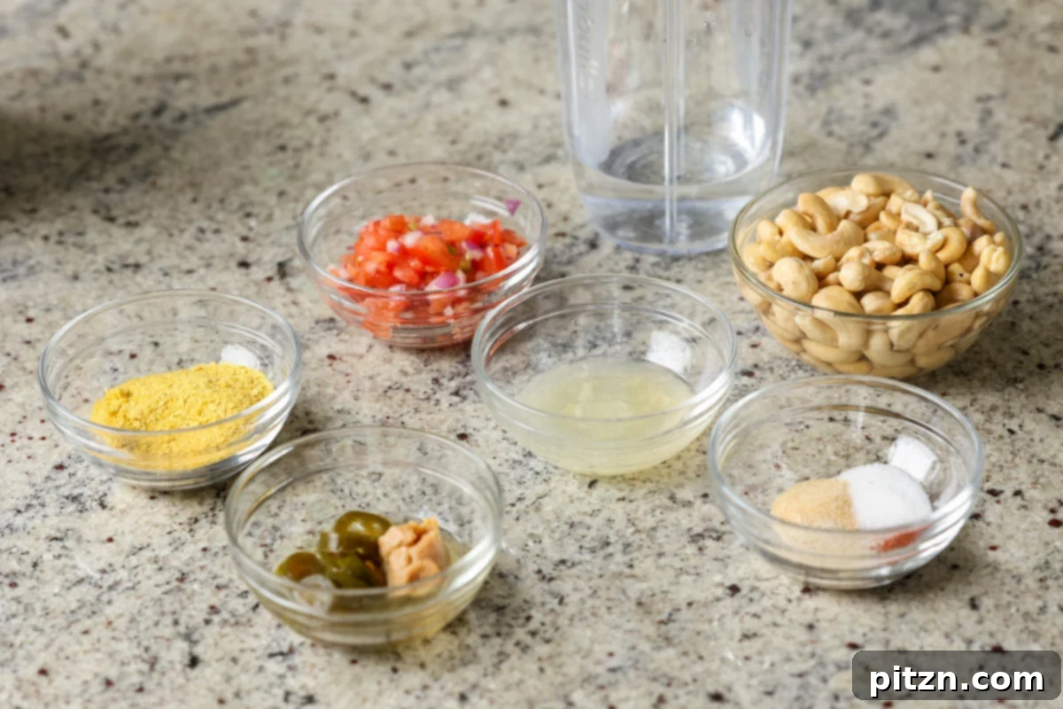 Amazing Cashew Nacho Cheese Gluten Free Oil Free Soy Free Choice 7 Raw cashews, diced tomatoes, nutritional yeast, and other key ingredients for nacho cheese laid out in bowls on a kitchen counter