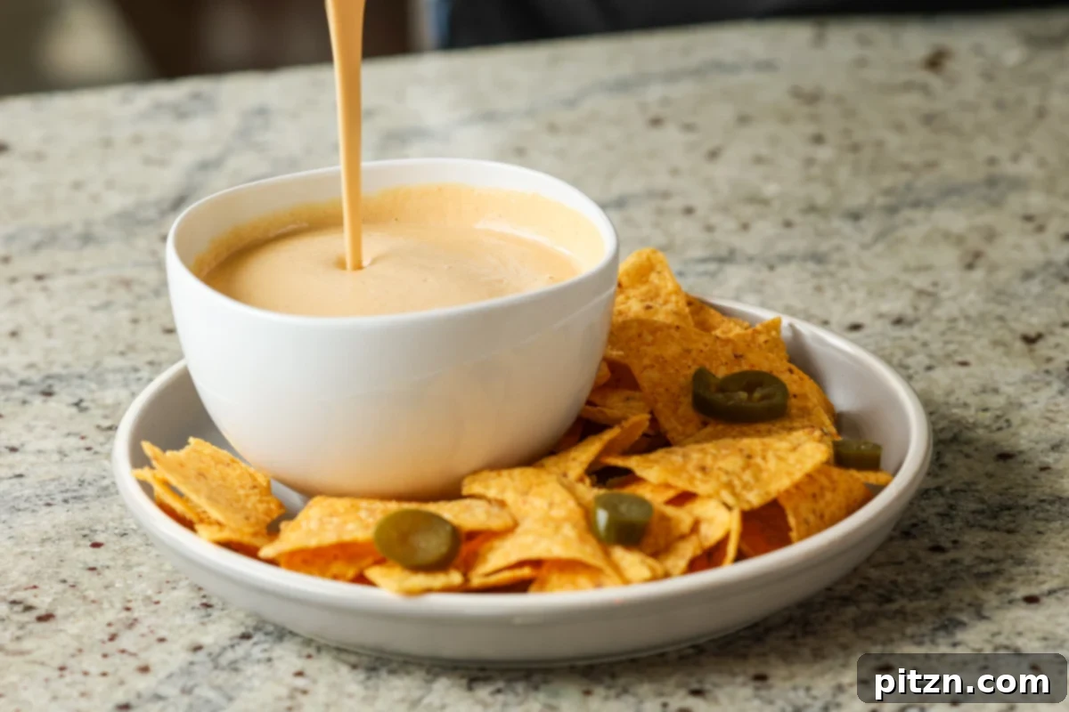 Amazing Cashew Nacho Cheese Gluten Free Oil Free Soy Free Choice 9 Thick, creamy cashew nacho cheese being carefully poured from a high-speed blender jug into a clean, white serving bowl
