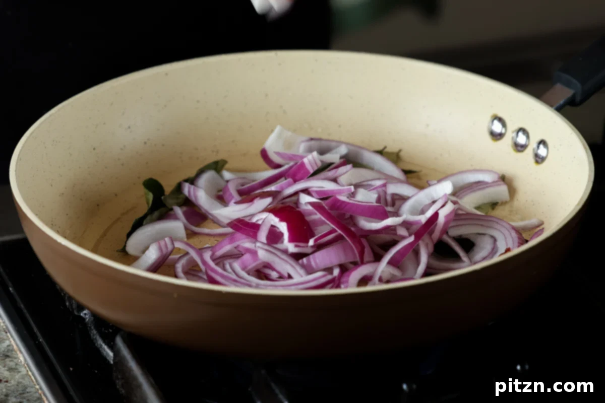 Tofu Kondattam: Crispy & Spicy South Indian Tofu 15 Adding sliced onions to the skillet with roasted spices