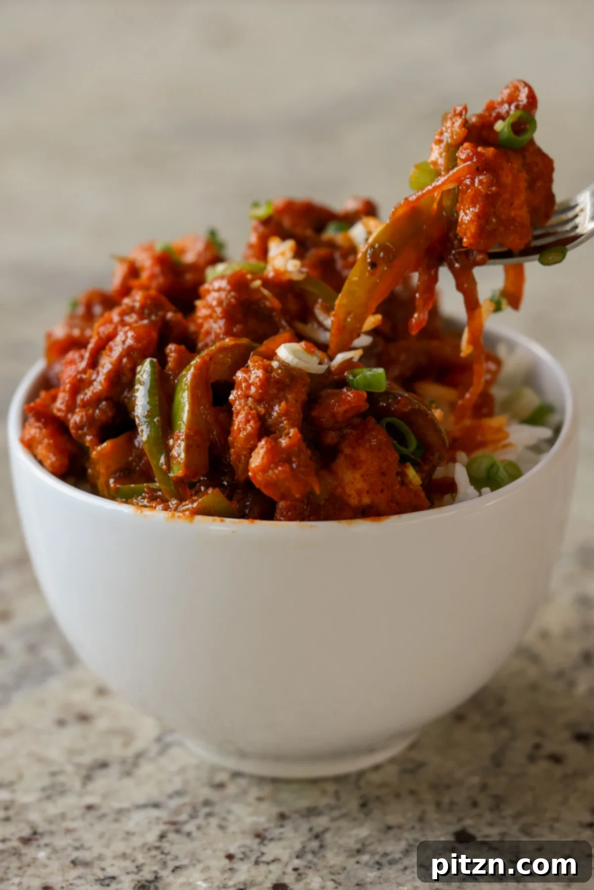 Tofu Kondattam: Crispy & Spicy South Indian Tofu 5 Fork lifting a piece of Tofu Kondattam from a bowl, ready to be eaten