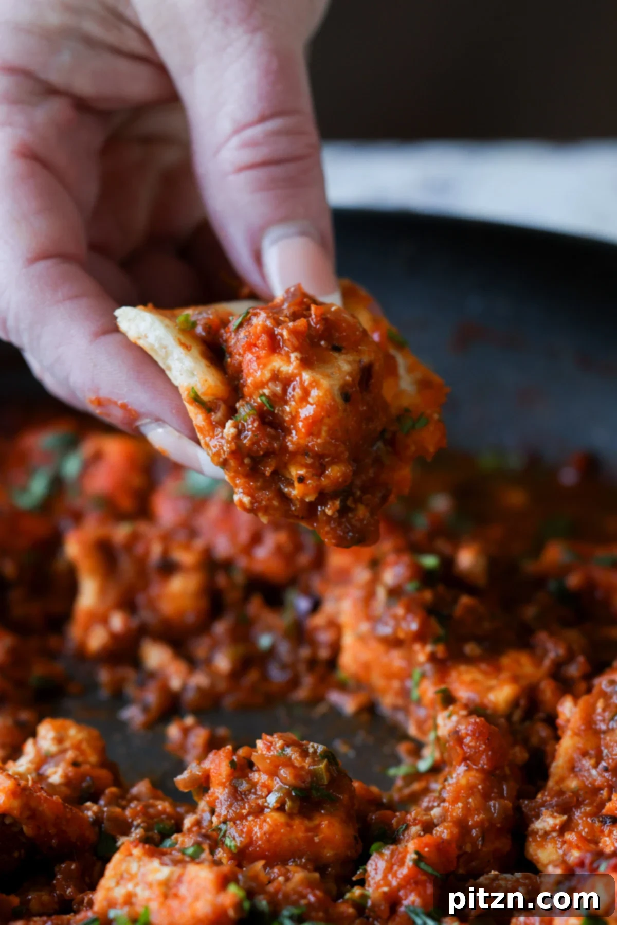 North Indian Smoky Rara Chicken Curry 4 hand scooping up rara chicken curry with a piece of naan