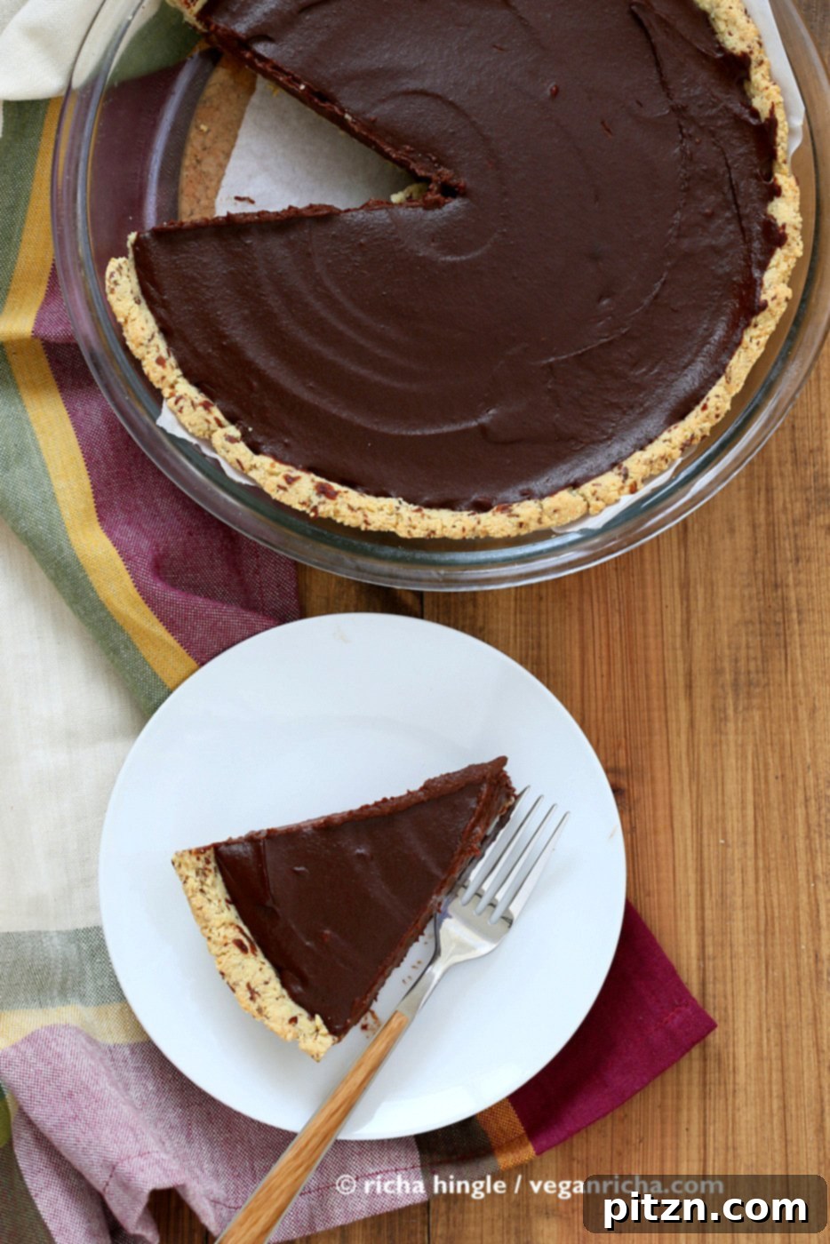 An inviting overhead view of a whole Vegan Chocolate Pumpkin Pie, baked to golden perfection in a classic Pyrex pie dish, with a single slice elegantly plated on the side, ready to be enjoyed as a festive dessert.