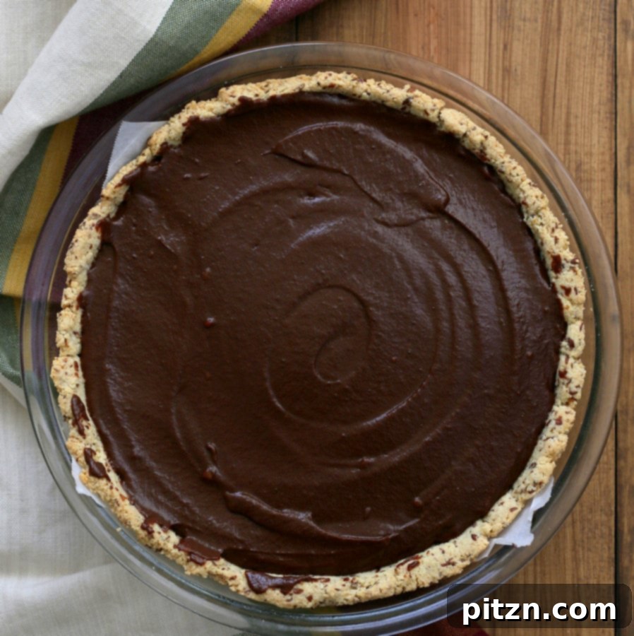 An appealing overhead shot of a whole Vegan Chocolate Pumpkin Pie resting in a Pyrex dish, freshly made and ready for chilling to set the creamy filling.