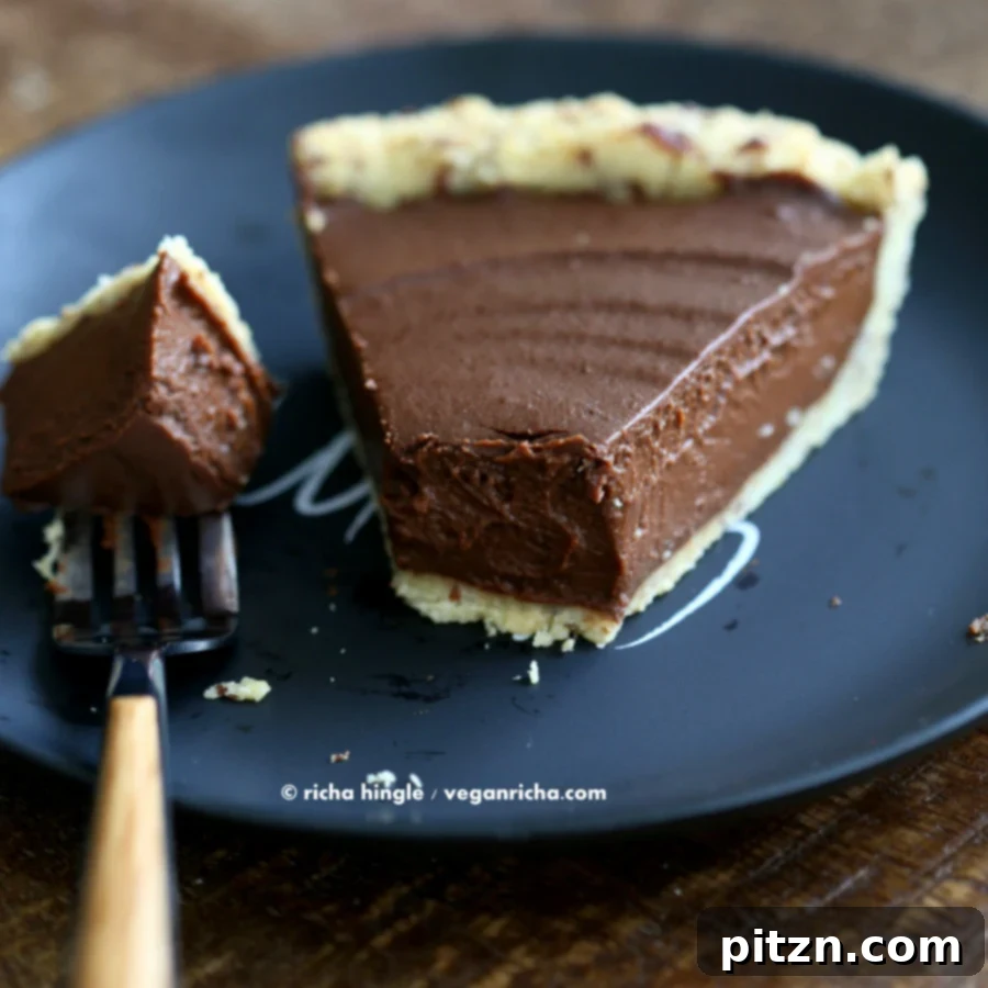 A delectable slice of Vegan Chocolate Pumpkin Pie, showing a fork with a piece missing, emphasizing its irresistible appeal, creamy texture, and the perfect bake of its almond flour crust. An inviting dessert ready to be savored.