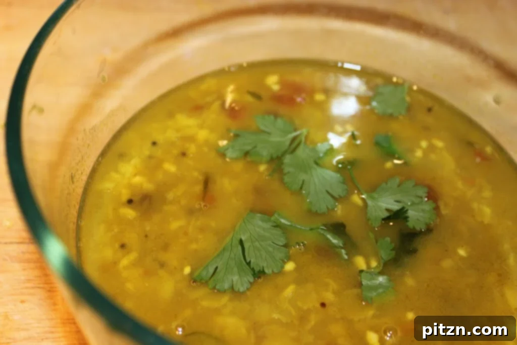 Two bowls of Teen Daal Tadka, garnished with fresh cilantro and a lime wedge