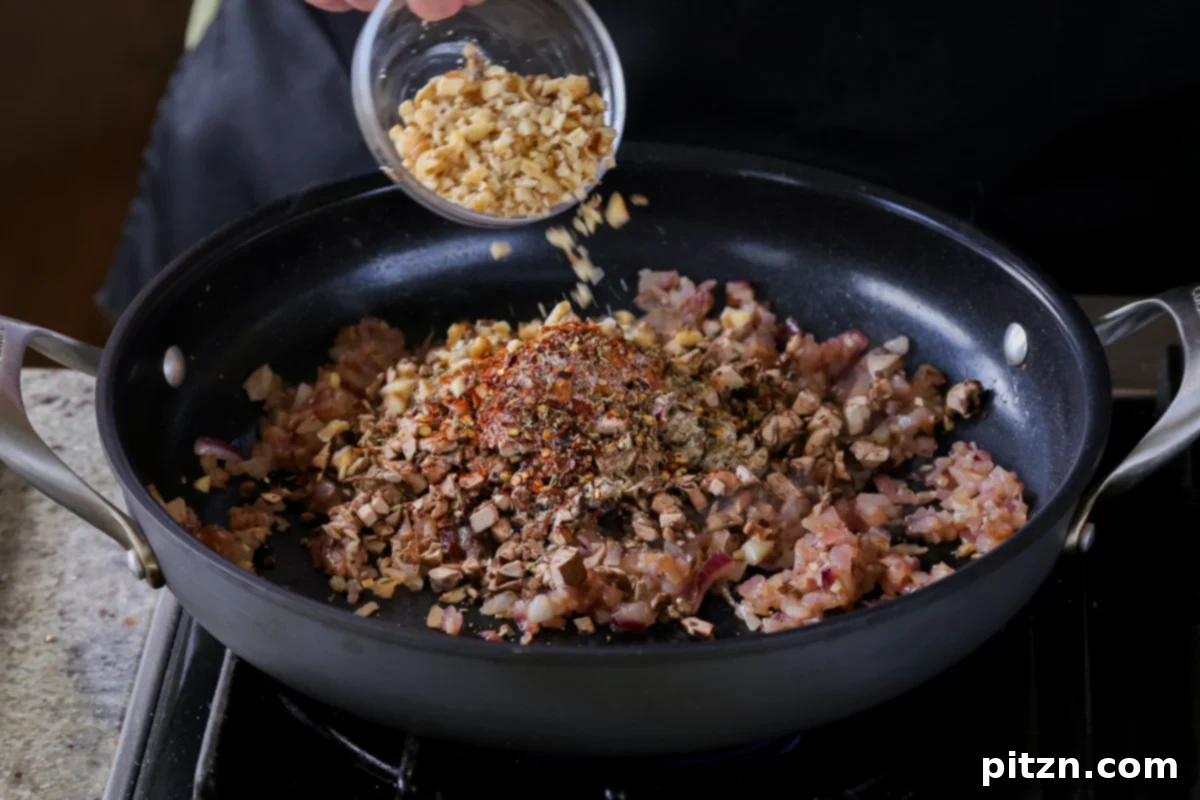 Weeknight Skillet Sausage and White Bean Pasta 12 Finely chopped walnuts being added to the skillet, completing the base for the rich vegan sausage crumble.