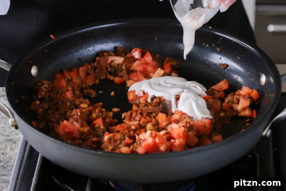 Weeknight Skillet Sausage and White Bean Pasta 15 Adding chopped fresh tomatoes and rich non-dairy cream to the vegan sausage mixture in the pan, forming the base of the creamy pasta sauce.