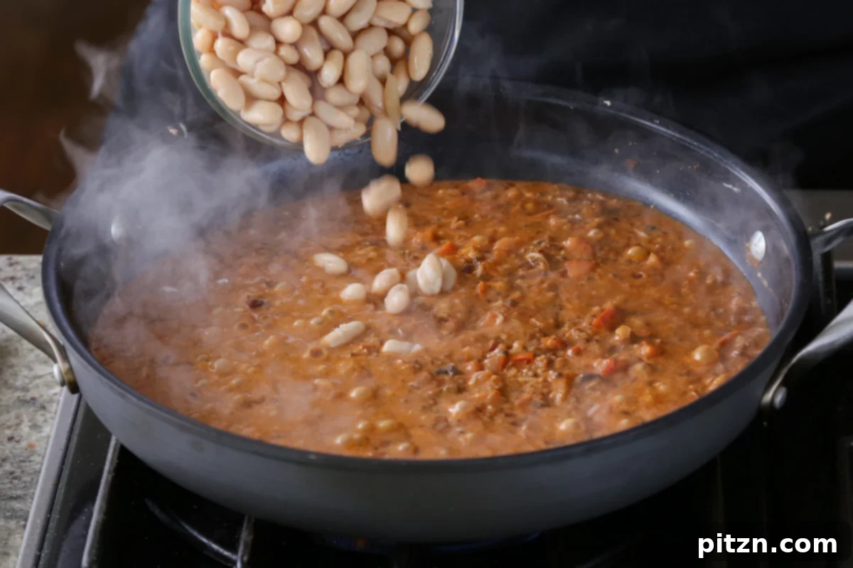 Weeknight Skillet Sausage and White Bean Pasta 18 Adding white cannellini beans to the rich vegan sausage pasta sauce, preparing for them to absorb all the delicious flavors.