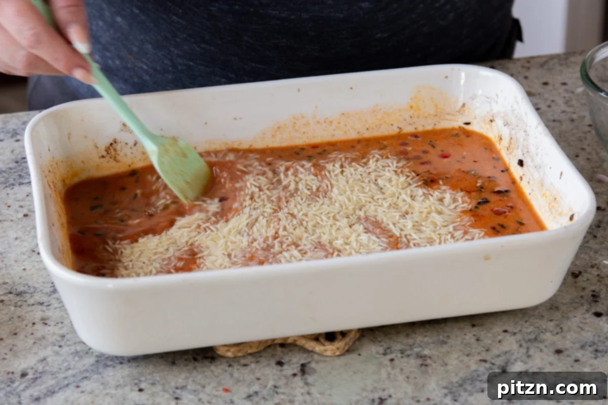Fragrant Tikka Masala Rice Bake with Golden Crispy Tofu 16 Washed basmati rice being added into the baking pan, on top of the tikka masala sauce and vegetables, before the final bake.