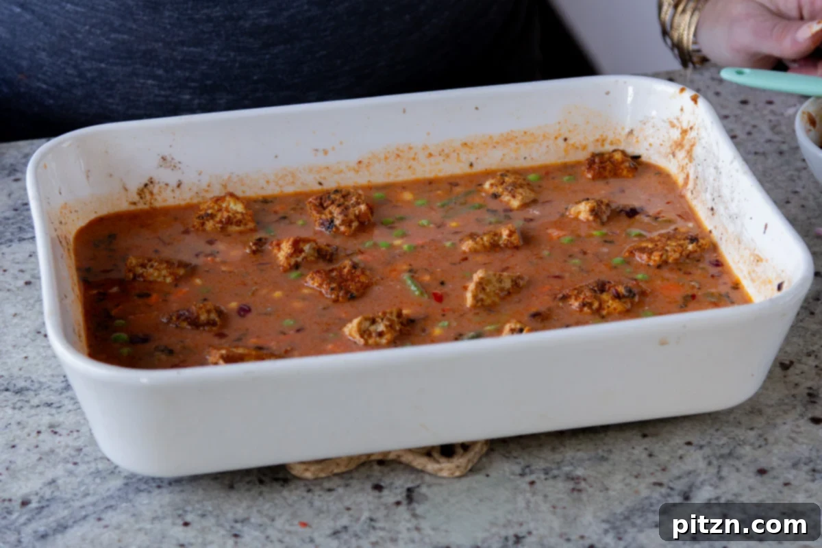 Fragrant Tikka Masala Rice Bake with Golden Crispy Tofu 19 Crispy baked tofu pieces being added back to the top of the Tikka Masala Rice in the baking pan, post-bake.