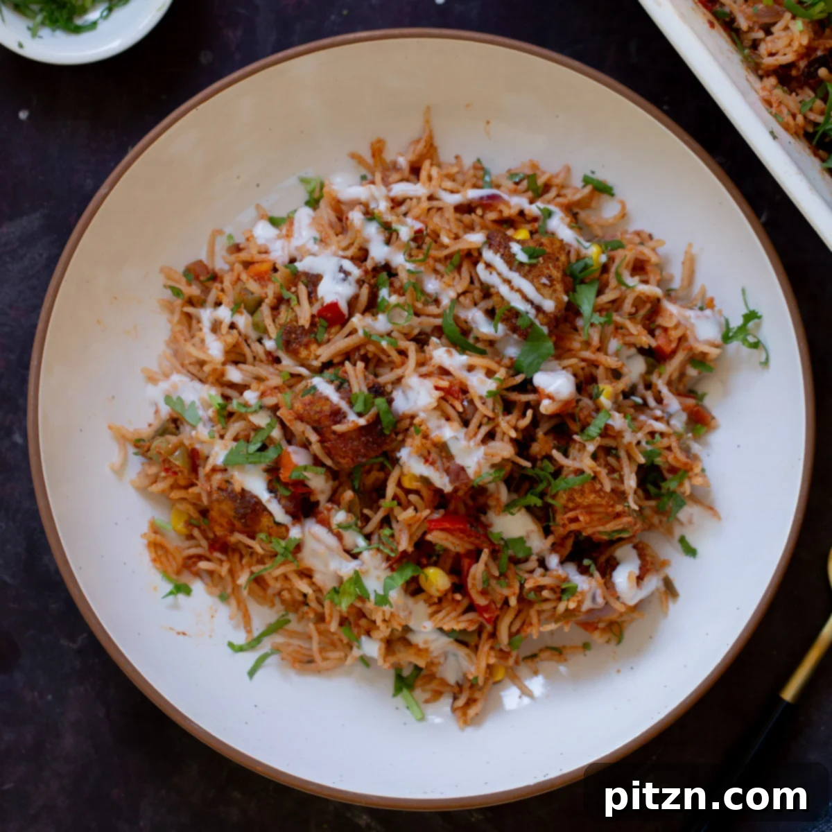 Fragrant Tikka Masala Rice Bake with Golden Crispy Tofu 22 A plate of Tikka Masala Rice Bake, beautifully garnished with fresh cilantro and a swirl of non-dairy yogurt, ready to be served.