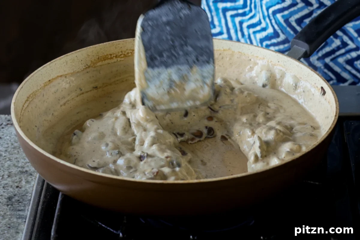 Stirring the cream sauce into the mushrooms in the pan, allowing it to simmer and thicken for the puff filling.