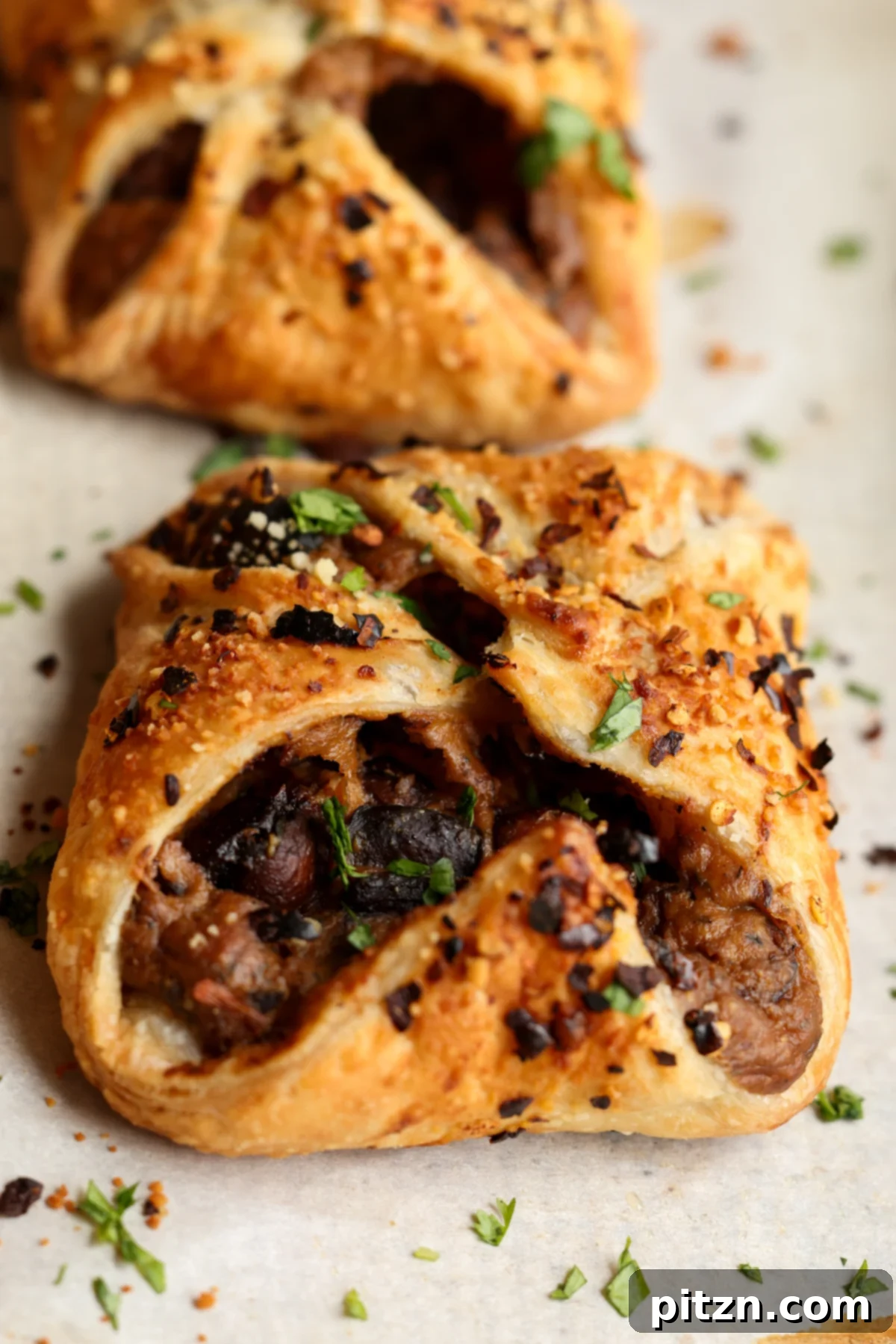 Side angle view of golden mushroom puffs on a baking sheet, showcasing the flaky pastry and hints of the creamy filling.