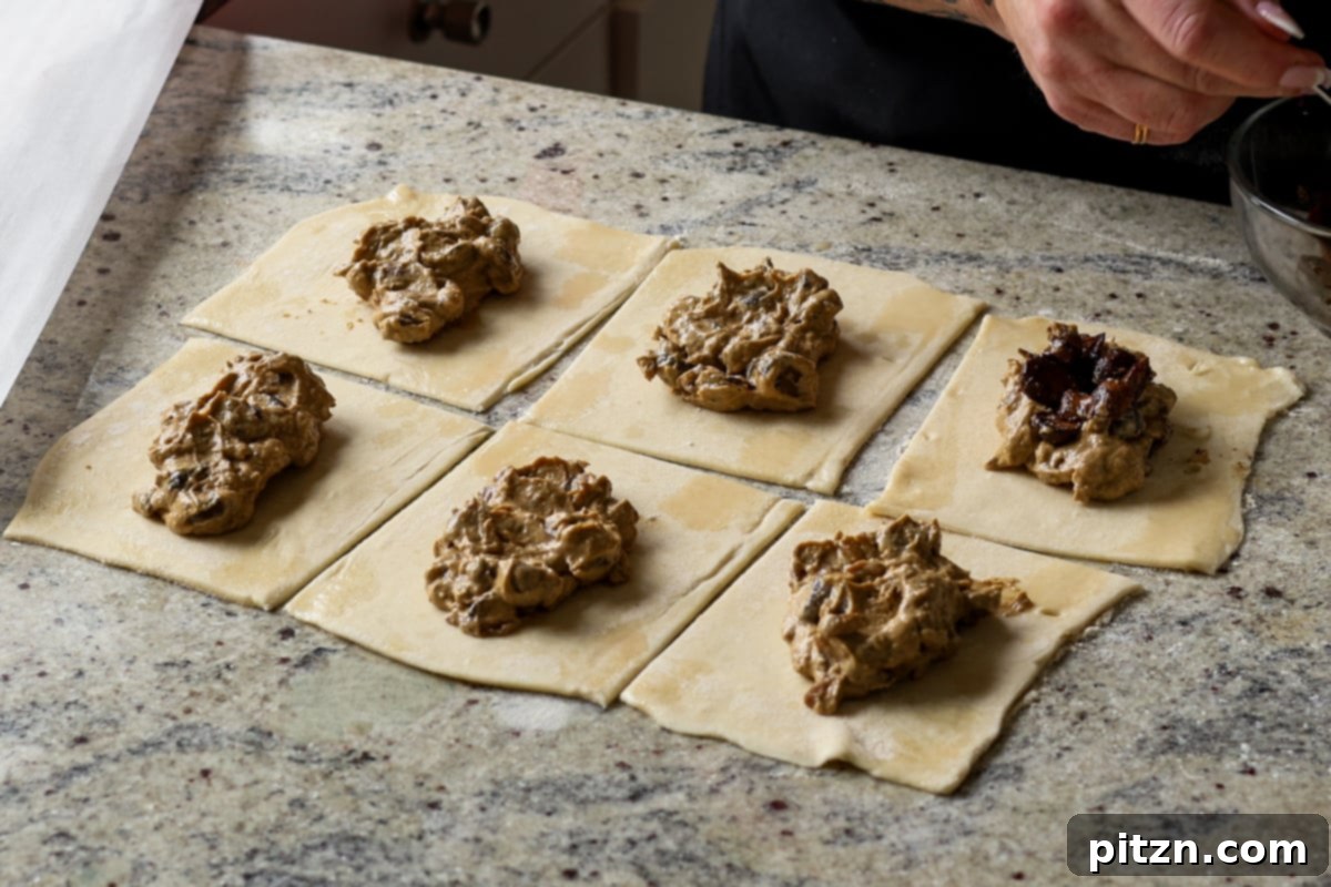 Topping the creamy mushroom filling with reserved sautéed mushrooms and a sprinkle of vegan Parmesan on puff pastry squares.