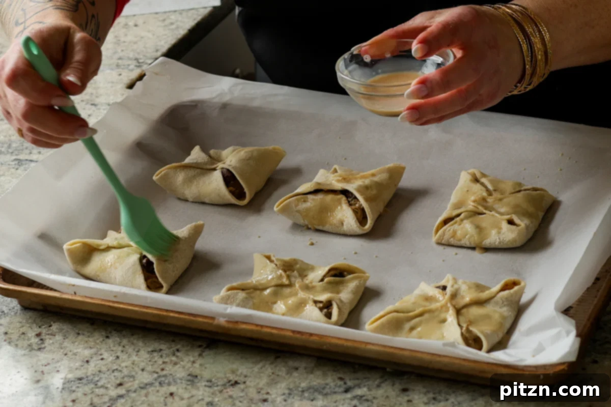 Brushing the tops of the assembled mushroom puffs with the non-dairy milk and maple syrup wash for a golden finish.