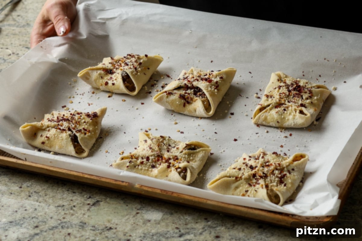 Assembled and topped mushroom puffs neatly arranged on a baking sheet, poised to go into the oven.