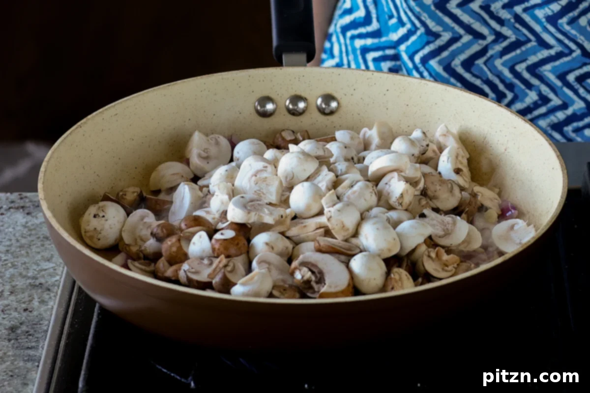 Adding thinly sliced mushrooms to the hot skillet with onions and garlic, preparing them for caramelization.