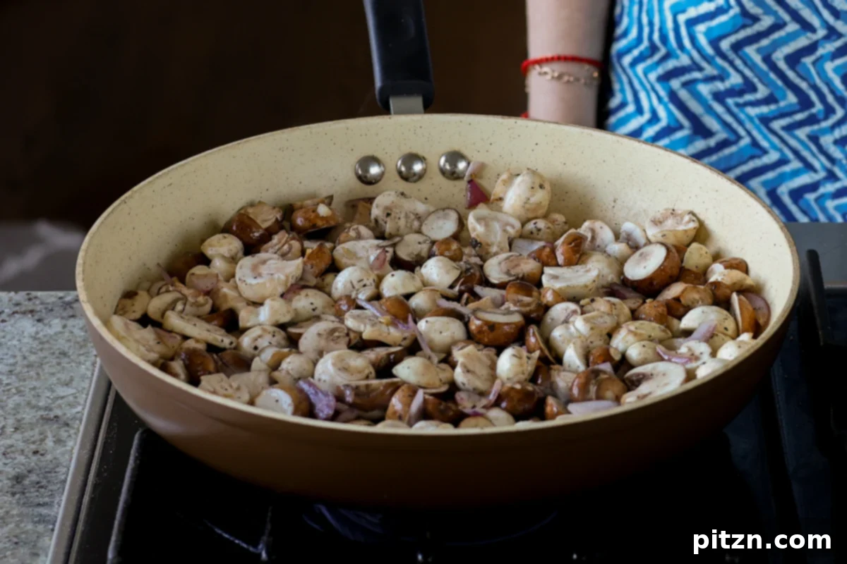 Partially cooked mushrooms in the pan, showing light browning on the edges, ready for further seasoning.