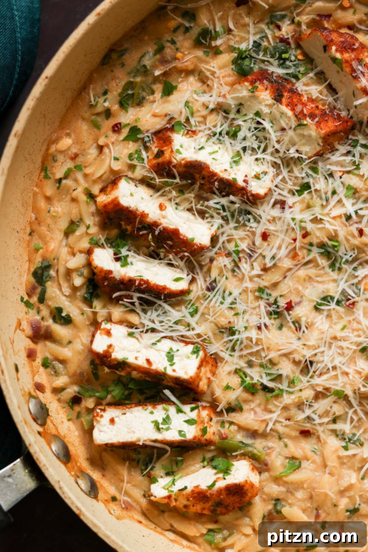 Golden Paprika Tofu with Creamy Garlic Parmesan Orzo 2 Close-up of garlic parmesan orzo in the pan with crispy paprika tofu, garnished with fresh herbs.