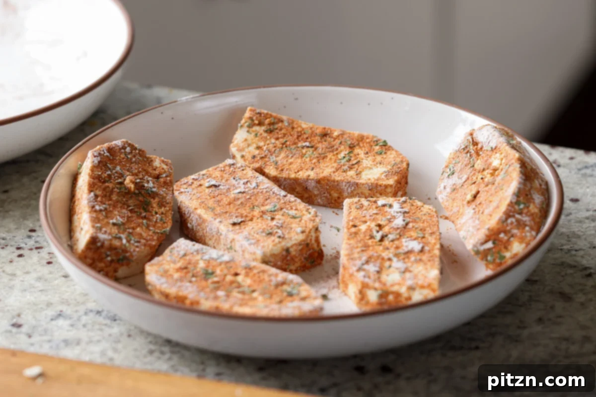 Golden Paprika Tofu with Creamy Garlic Parmesan Orzo 11 Coated tofu slices neatly arranged on a plate, ready for pan-searing.