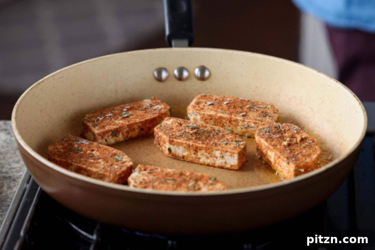 Golden Paprika Tofu with Creamy Garlic Parmesan Orzo 12 Carefully placing coated tofu slices into a hot skillet with oil.