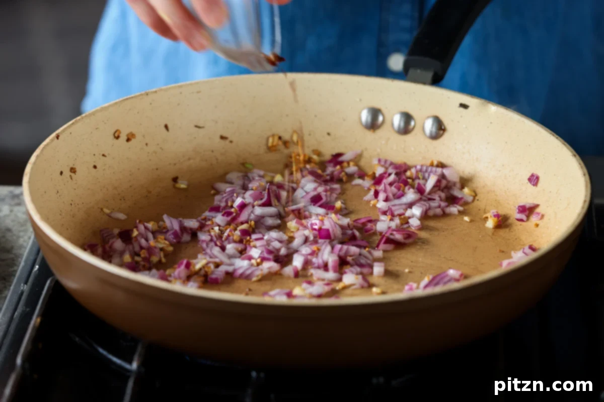 Golden Paprika Tofu with Creamy Garlic Parmesan Orzo 16 Chili flakes stirred into the aromatic mixture in the pan, adding a hint of spice.