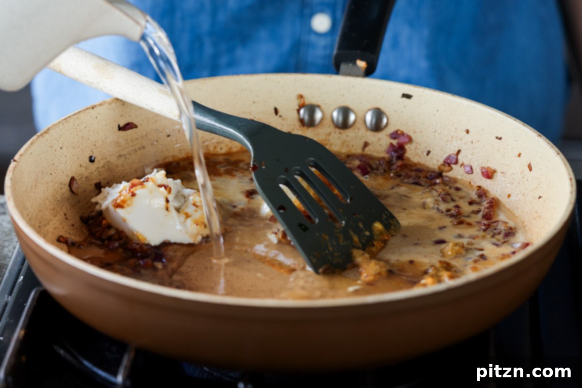 Golden Paprika Tofu with Creamy Garlic Parmesan Orzo 20 Adding vegan cream cheese and water to the pan to create a rich, creamy sauce.