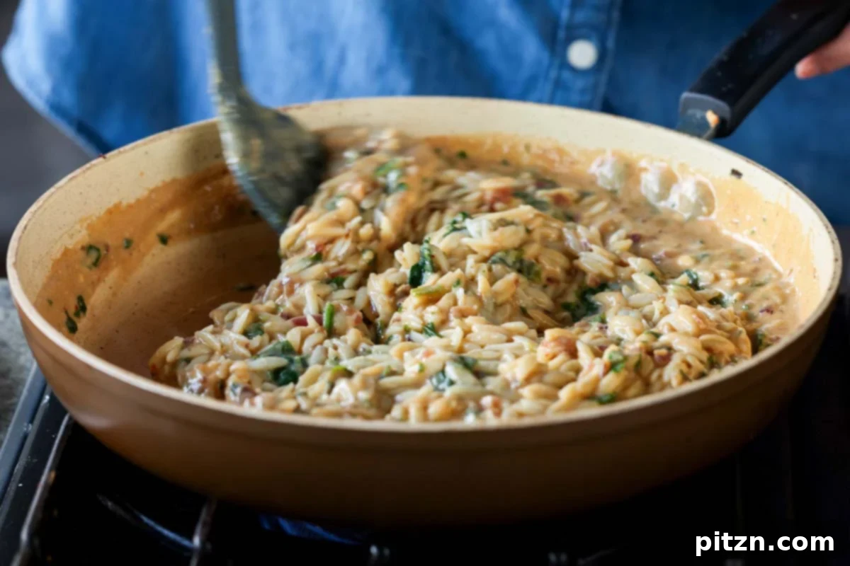 Golden Paprika Tofu with Creamy Garlic Parmesan Orzo 25 Mixing the orzo, spinach, and sauce together in the pan, ensuring everything is coated.
