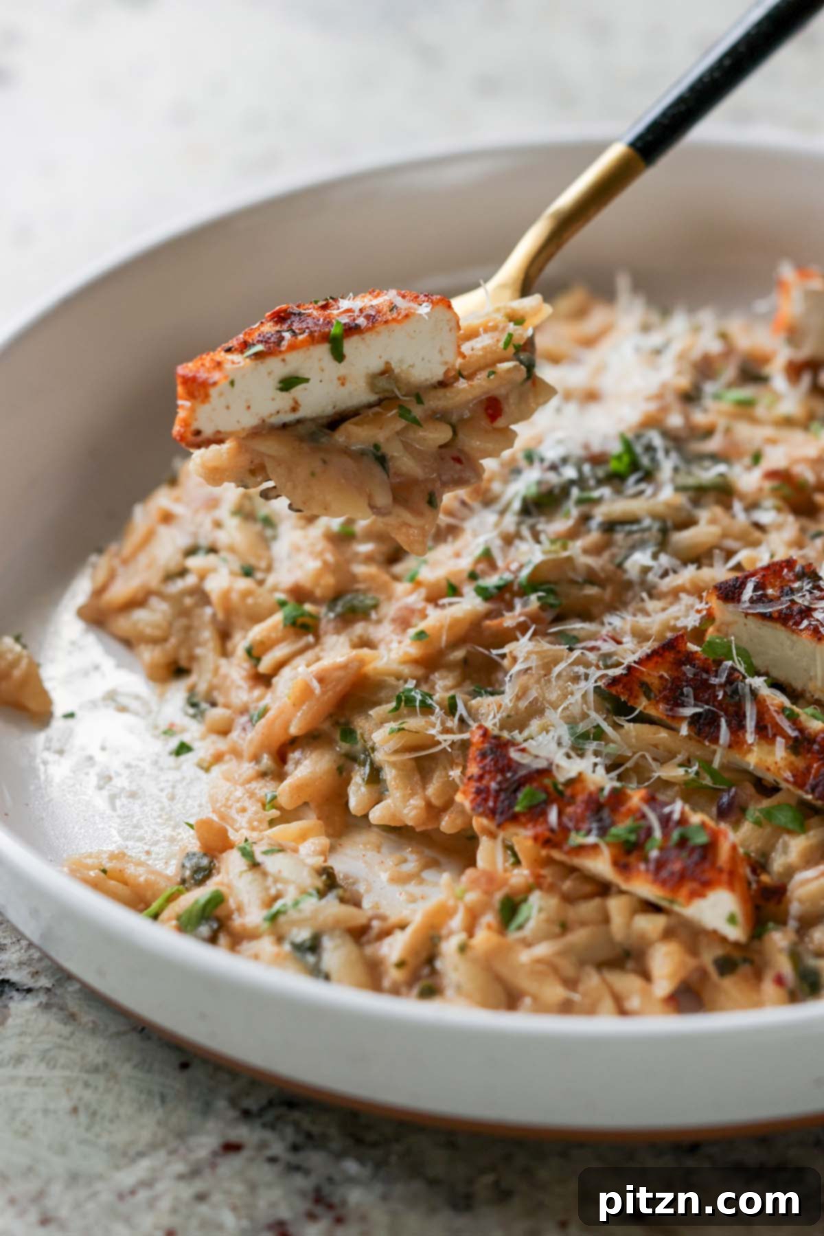 Golden Paprika Tofu with Creamy Garlic Parmesan Orzo 5 Fork taking a bite of creamy garlic parmesan orzo with a piece of crispy tofu.