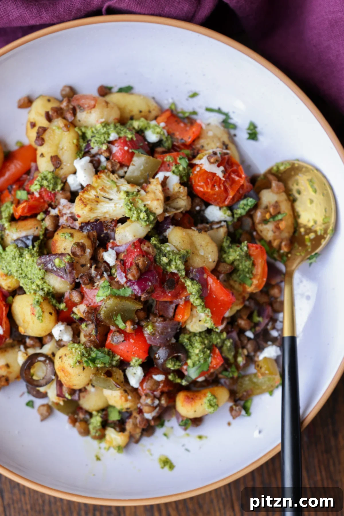 One-Pan Mediterranean Gnocchi: No Boil, Big Flavor 4 A bowl of Mediterranean sheet pan gnocchi, garnished with fresh basil and vegan feta, with a spoon ready to serve.