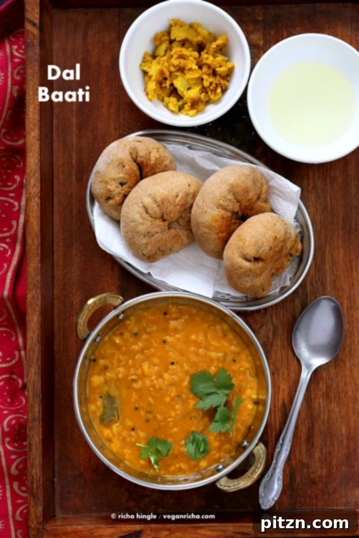 Traditional Dal Baati served with lentil soup and fresh cilantro, a vegan Indian meal.