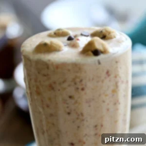 A tall glass of Vegan Chocolate Chip Cookie Dough Blizzard Milkshake, topped with whipped cream and chocolate chips. Gluten-free option.