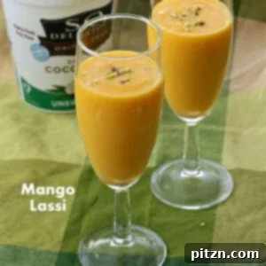 A glass of creamy Vegan Mango Lassi, an Indian mango yogurt smoothie, garnished with a sprinkle of cardamom or saffron. Dairy-free, gluten-free.