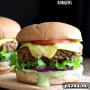 Spiced Lentil Walnut Burgers with avocado ranch sauce, garnished with fresh cilantro on a white plate. Vegan, soy-free, easily gluten-free.
