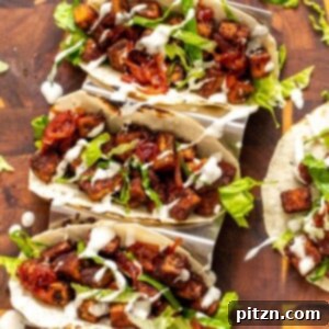 Overhead shot of two delicious Blackened Tofu Tacos with caramelized BBQ onions, garnished with fresh cilantro and lime wedges.