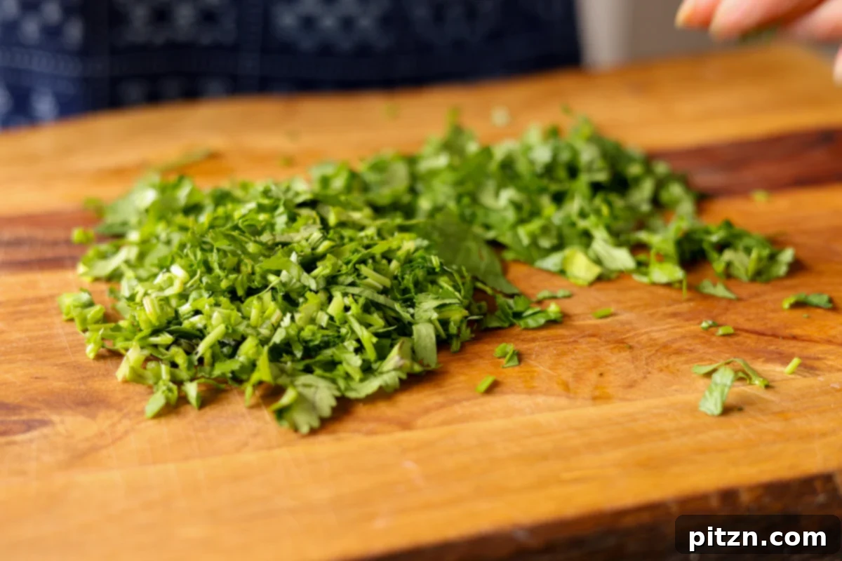One Pan Chicken Style Braised Tofu and Vegetables 20 Finely chopped fresh herbs, likely cilantro and parsley, neatly piled on a wooden cutting board, ready for the sauce.