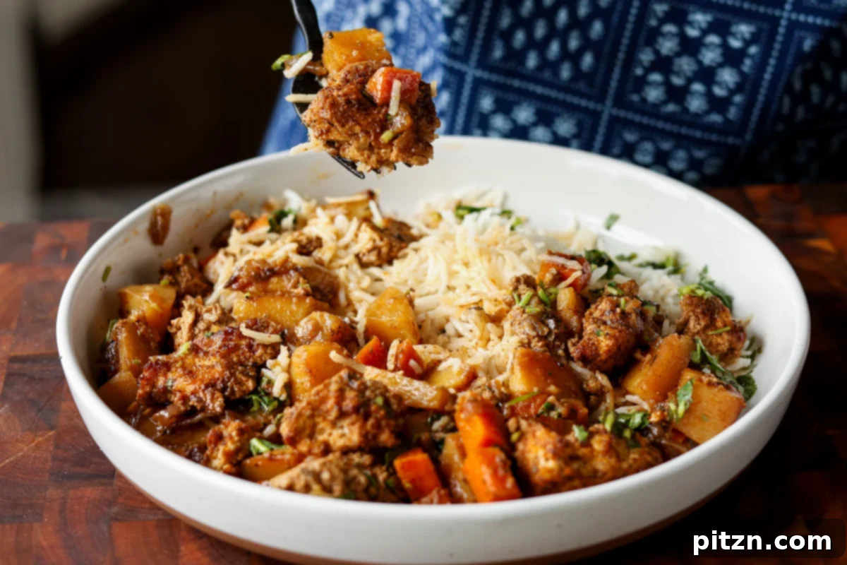 One Pan Chicken Style Braised Tofu and Vegetables 23 A fork piercing a piece of braised tofu, showcasing its tender interior, with vegetables, rice, and herb sauce in the background.