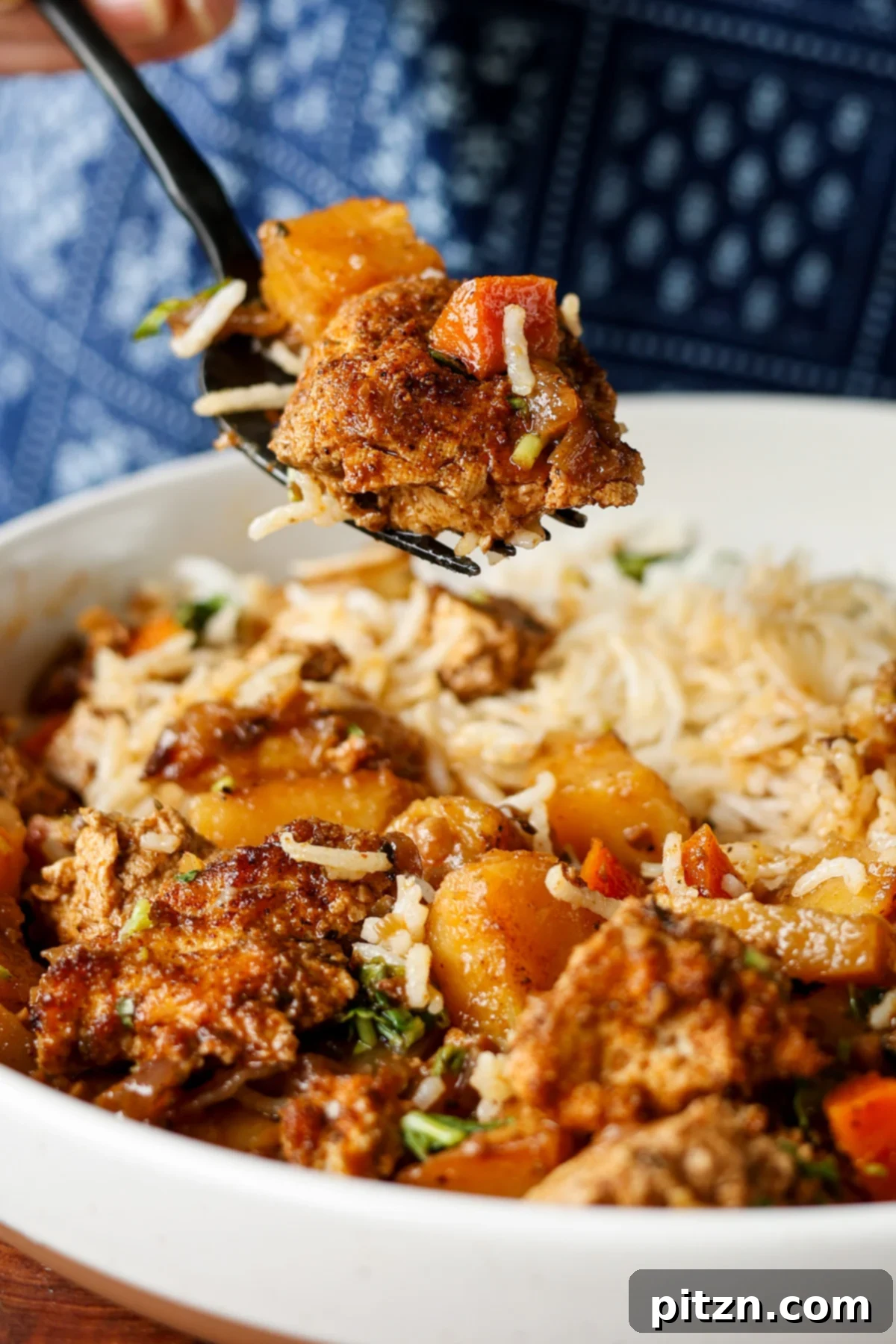 One Pan Chicken Style Braised Tofu and Vegetables 5 A fork lifts a bite of braised tofu and vegetables, showcasing the tender pieces and rich sauce, with rice and herb sauce in the background.