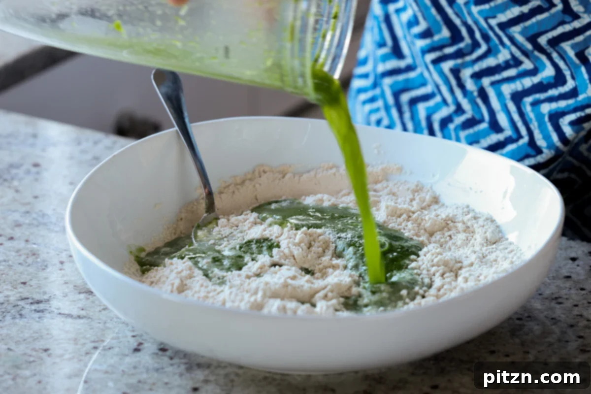 Yeast-Free Spinach Paratha Flatbread 12 Pouring the vibrant green spinach purée into the bowl of dry ingredients for the paratha dough.
