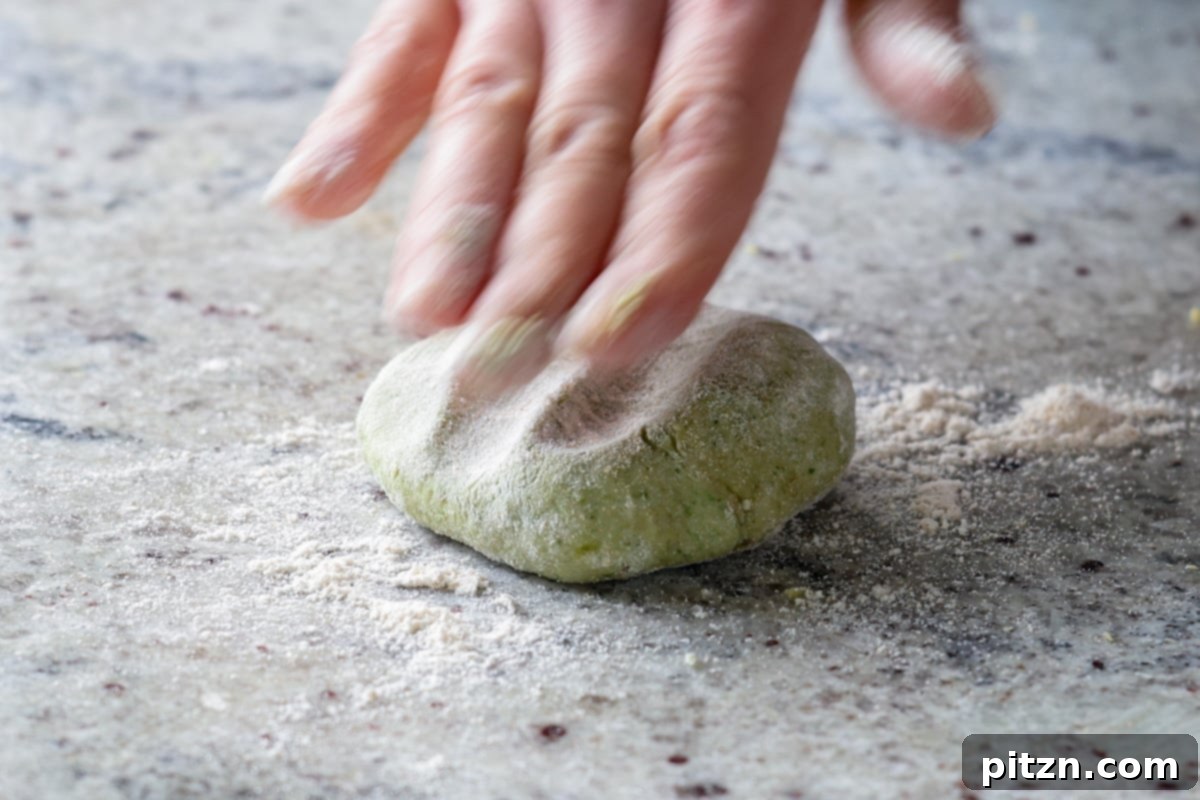 Yeast-Free Spinach Paratha Flatbread 22 Flattening a dough ball with the palm of a hand, preparing it for the rolling process.