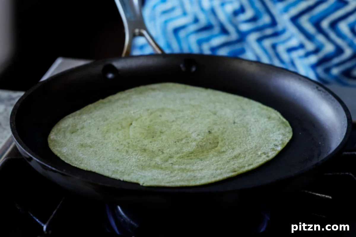 Yeast-Free Spinach Paratha Flatbread 35 Gently placing a spinach paratha onto a hot skillet for cooking.
