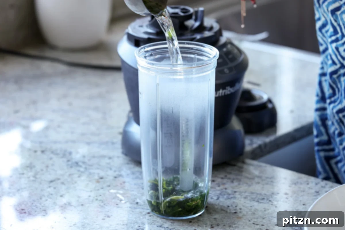 Yeast-Free Spinach Paratha Flatbread 8 Adding blanched spinach and water to a blender to create a smooth purée for the paratha dough.