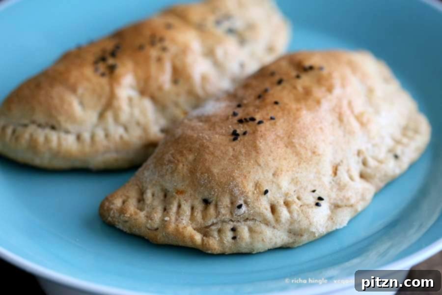 Two freshly baked Vegan Naan Calzones, golden brown and garnished with herbs, ready to be served as a healthy vegan meal.