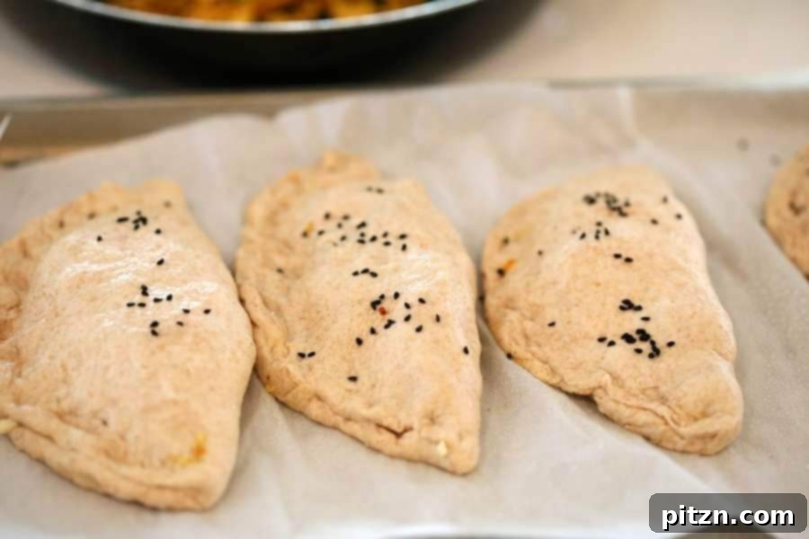 A vegan naan calzone being filled with spicy tofu and pea scramble, then sealed with a fork.